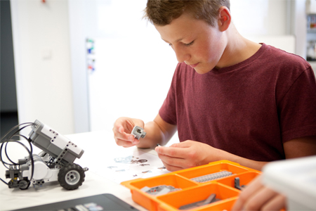 Junger der in der Wissenswerkstatt in der SEE.STATT Friedrichshafen einen Roboter zusammenbaut.