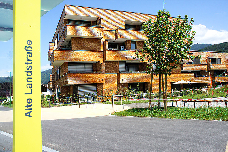 Foto von Wohnanlagen in der Alten Landstraße in Röthis mit einer Bushaltestelle im Vordergrund. Foto von Wohnanlagen in der Alten Landstraße in Röthis mit einer Bushaltestelle im Vordergrund.