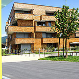 Foto von Wohnanlagen in der Alten Landstraße in Röthis mit einer Bushaltestelle im Vordergrund.